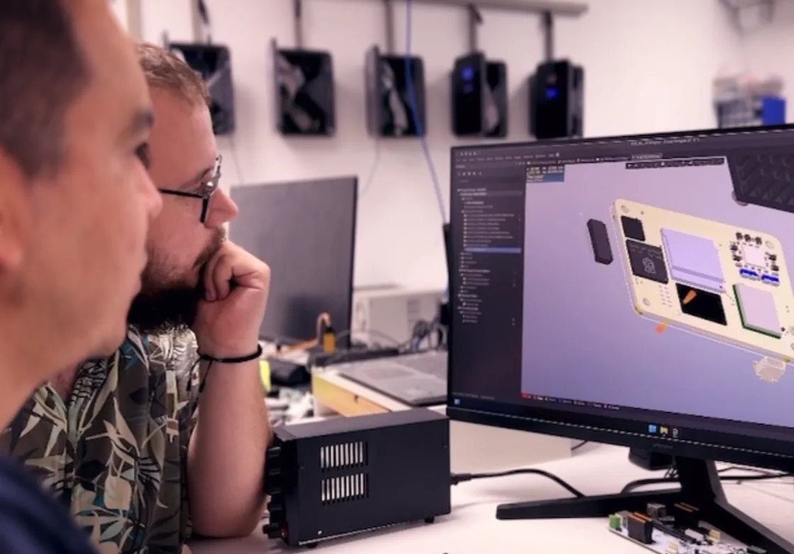Dos ingenieros de V2C revisando en pantalla el diseño de la placa electrónica de un cargador