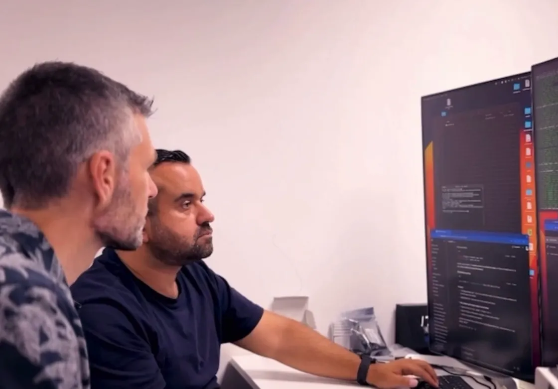 Dos ingenieros de V2C desarrollando el software del cargador frente a varios monitores