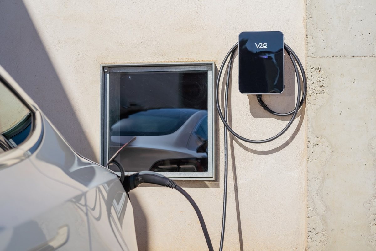 Wallbox Trydan an einer Hauswand lädt ein Elektroauto über ein Typ-2-Ladekabel